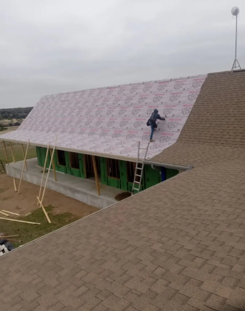 Worker preparing underlayment for a metal roof installation in Daly City